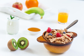 Healthy breakfast with bowl of cereal, orange juice, milk, and fruits.
