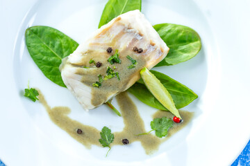 Steamed cod fillet with sorrel sauce and salad leaves.