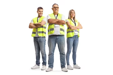Foto op Canvas Full length portrait of two men and a woman wearing a reflective safety vests and posing with crossed arms © Ljupco Smokovski