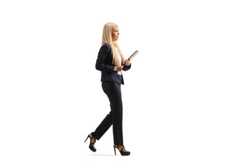 Full length profile shot of a young professional woman in suit and high heels walking