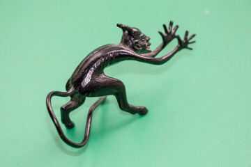A small metal sculpture of the devil with a tail showing his tongue