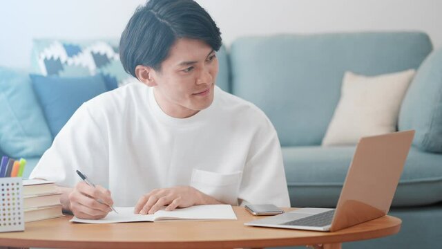 ノートパソコンでオンライン授業を受ける男性