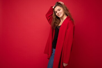 Naklejka premium Young beautiful european stylish brunette woman wearing red cardigan isolated over red background with positive sincere emotions. Simple and natural looking at the camera. Free space