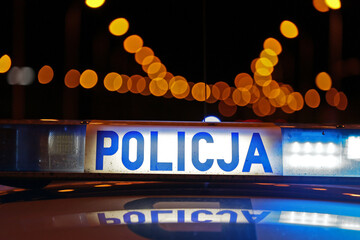 Sygnalizator błyskowy niebieski na dachu radiowozu policji polskiej w nocy.  © FotoDax