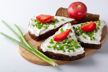Fototapeta na wymiar Slices of bread with cottage cheese, onion and tomatoes on wooden plate on white background