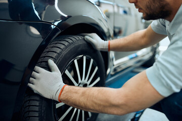 Close-up of repairman changes car tire at auto service workshop.