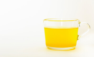 yellow tea in a transparent mug on a light background