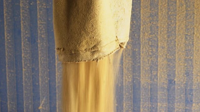 Compound feedstuff to feed the Livestock. Compound feedstuff is falling out of a bag on the ground. Compound feedstuff will provide animals with necessary nutrients. Animal Husbandry. Barn.