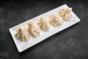 Cooked Khinkali on a white plate on a dark background