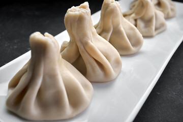 Cooked Khinkali on a white plate on a dark background