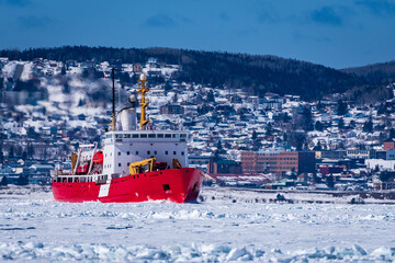 Coast Guard icebreaker at work near small coastal community in eastern Quebec, Canada.
