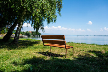 Wooden bench on the grassy beach of a recreational destination by the lake in the park