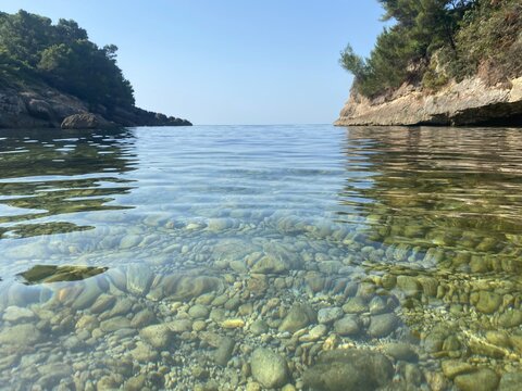 Pebble beach of Mediterranean sea. Beautiful calm clear water. Rocky coast of the sea. Summer. Relax. Tranquility.