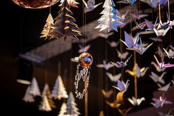 Lots of origami swans hanging from the roof, seen from underneath in a softly illuminated room