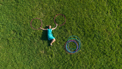 Aerial view of a woman laying on grass with Hula Hoop at public park in Zagreb downtown, Croatia.