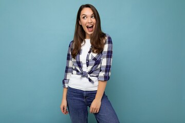 Young beautiful brunet woman. Trendy lady in casual summer hipster shirt . Positive female shows facial emotions. Funny model isolated on blue background with free space