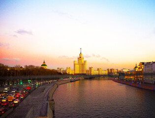 Fototapeta premium view of the sunset on the river, a residential skyscraper on Kotelnicheskaya Embankment, Moscow River, Bolshoy Ustinsky bridge. Moscow, Russia
