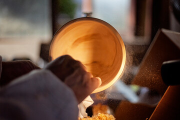 A wooden bowl being turned by a man on a woodturning lathe.A craftsman at work.Sawdust is flying.