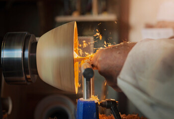 A wooden bowl being turned by a man on a woodturning lathe.A craftsman at work.Sawdust is flying.