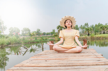 Beautiful young woman doing yoga in nature. Girl sitting on a wooden bridge.