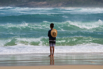 Rio de Janeiro child wearing a straw hat watching the waves of the marna beach located at Post 12, known as 