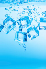 Ice cubes in blue water create bubbles that float to the surface, blue liquid.