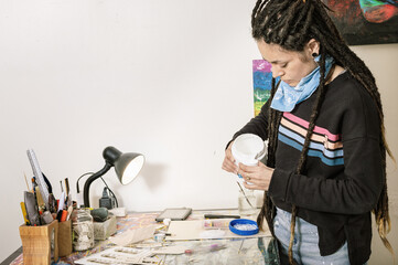 young white hispanic latin art director girl in her studio, pouring white glue on plastic packaging