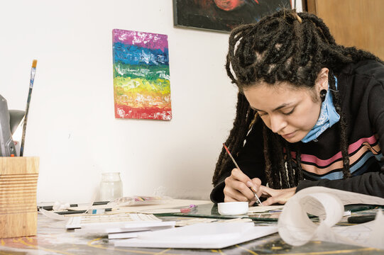 young white girl hispanic latin art director, gluing paper and plastic with a white brush and glue.
