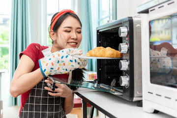Beautiful Asian woman picking up homemade croissant bread. Freshly baked hot and deliciously fragrant out of the oven bakery.