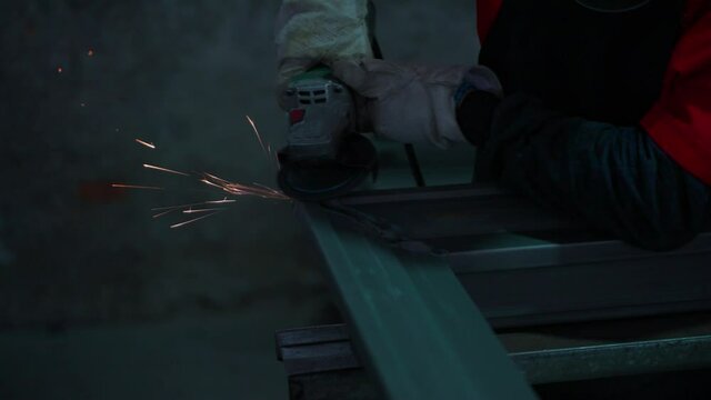 close up worker hand wear glove holding grinder griding metal in the factory