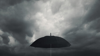 Black umbrella against dark cloud background. Ready to deal with the drop from the economic crisis. Weather forecast and natural disaster. Protection from the depression storm. Business metaphor. - obrazy, fototapety, plakaty