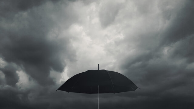 Black umbrella against dark cloud background. Ready to deal with the drop from the economic crisis. Weather forecast and natural disaster. Protection from the depression storm. Business metaphor.