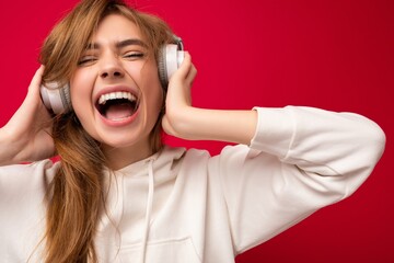 Shot of attractive crazy positive young blonde woman wearing white hoodie isolated over colourful...