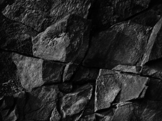 Destroyed cracked mountain surface. Close-up. It looks like a stone wall. Black grunge background...
