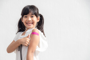 Asian little girl showing his arm after got vaccinated or inoculation, child immunization, covid delta vaccine concept