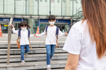 Portrait image of little cute Asian children siblings wearing a face mask and take a school bag. Back to school and kids. Childhood