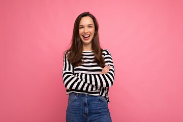 Photo portrait of young beautiful smiling hipster brunette woman in trendy pullover. Sexy carefree female person posing isolated near pink wall with empty space in studio. Positive model with natural