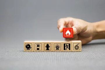 Tuinposter Fire prevention, Cube wooden toy block stack with prevent icon with door exit sing or fire escape with fire extinguisher and emergency protection symbol for safety and rescue in the building. © Eakrin