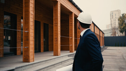 Architect with blueprint standing near building on urban street