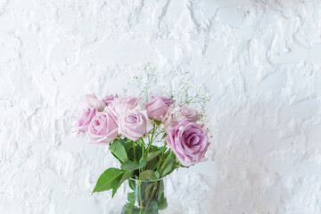 a bouquet of light pink roses on a white wall background