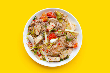 Dish of spicy vermicelli salad on yellow background.