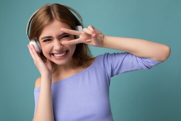 Photo of charming smiling sexy young blonde woman wearing blue crop top isolated on blue background...