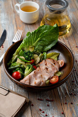 Skinny dinner in a restaurant: baked poultry salad with broccoli and cherry tomatoes, close up for menu