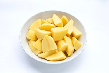 Fresh potato cut into pieces in bowl on white background.
