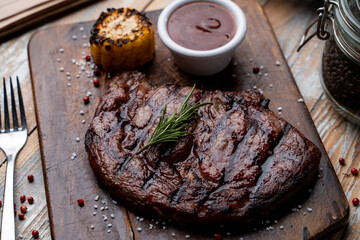 Barbecue steak with grill traces and baked corn, served with tomato sauce on a wooden rustic table