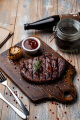 Juicy buffalo steak with grill traces and baked corn,on a dark wooden cutting board