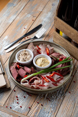 Cold meat delicatessen platter with pork fat, prosciutto, parma and ham, wooden rustic table, green onion