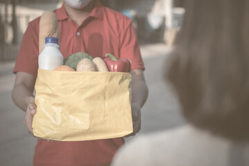 Fototapeta na wymiar Food delivery from store to door. Courier in medical gloves gives products to client at home, cropped. express delivery, quarantine, virus outbreak, takeaway food delivery concept.