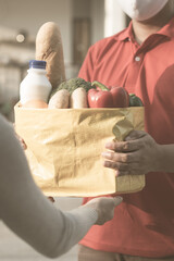 Food delivery from store to door. Courier in medical gloves gives products to client at home,...