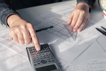 Architect working on blueprint. Architects workplace - architectural project, blueprints, ruler, calculator, laptop and divider compass. Construction concept. Blue print is fake only for stock photo.